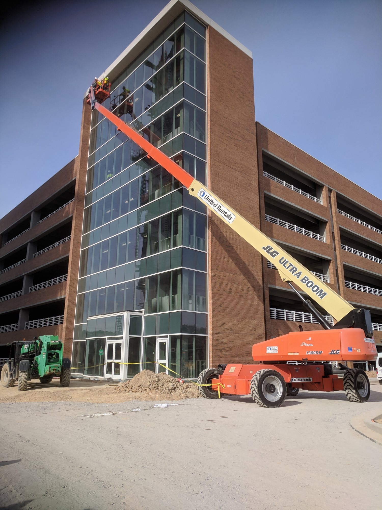 80-foot boom lift puts a crew at the top of a new parking deck stair tower to clean the curtain wall glass.