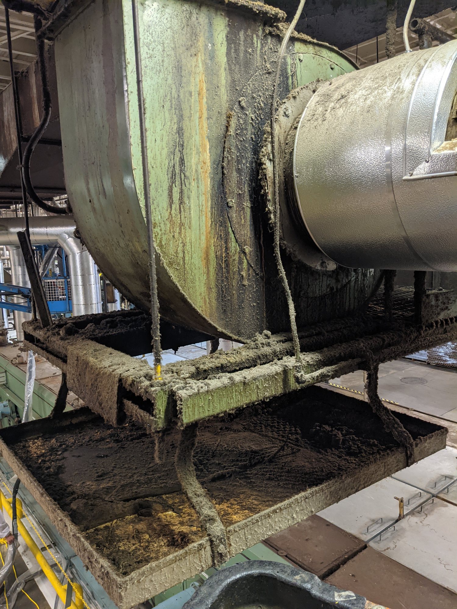 Cotton lint cakes a textile plant blower housing, duct and drip pan before cleaning.