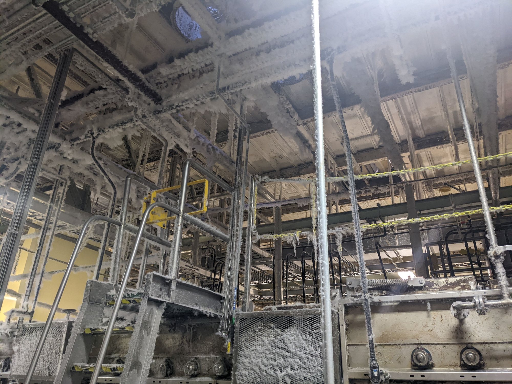 Before cleaning: pipes, trays and steel above a textile machine buried under thick cotton lint.