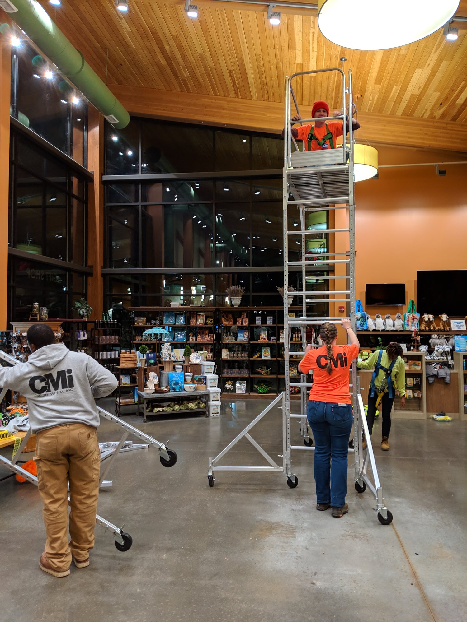 Clean Metro crew high dusting from a rolling tower over retail stock at night