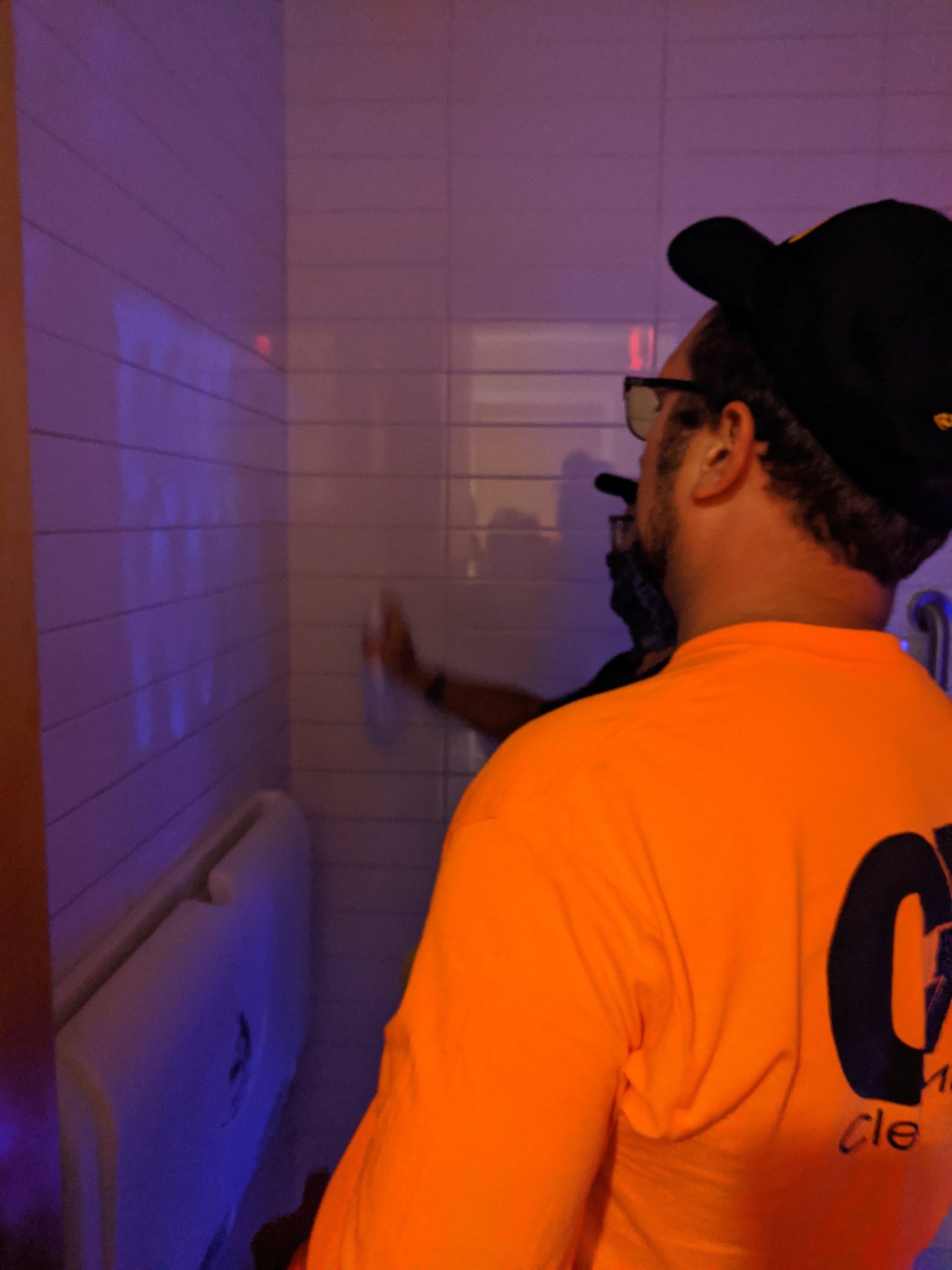 Under UV light, a CMI tech checks a restroom wall for residue the eye can't see.