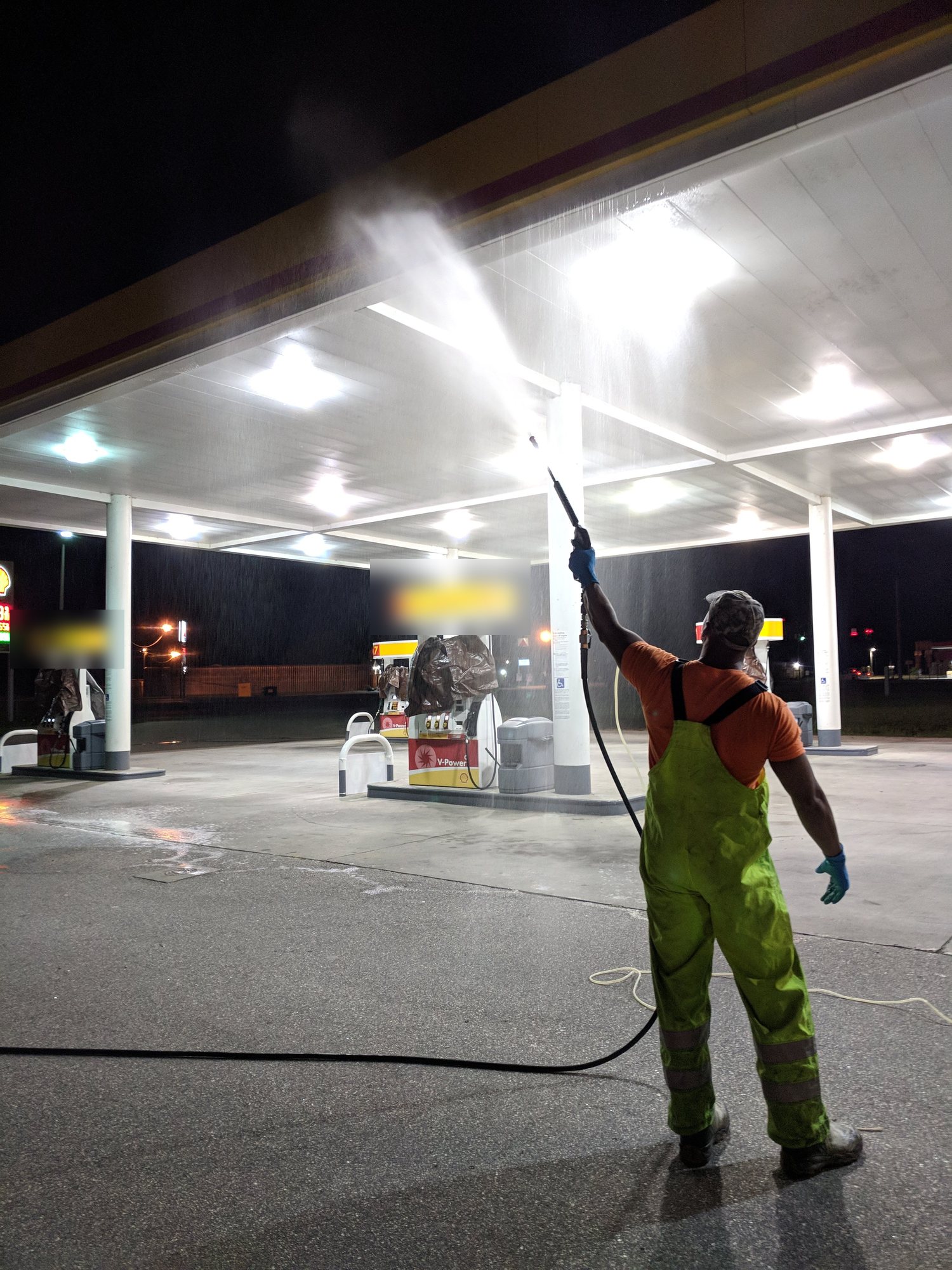 A CMI tech pressure washes the underside of a fuel station canopy overnight, when the pumps are quiet.