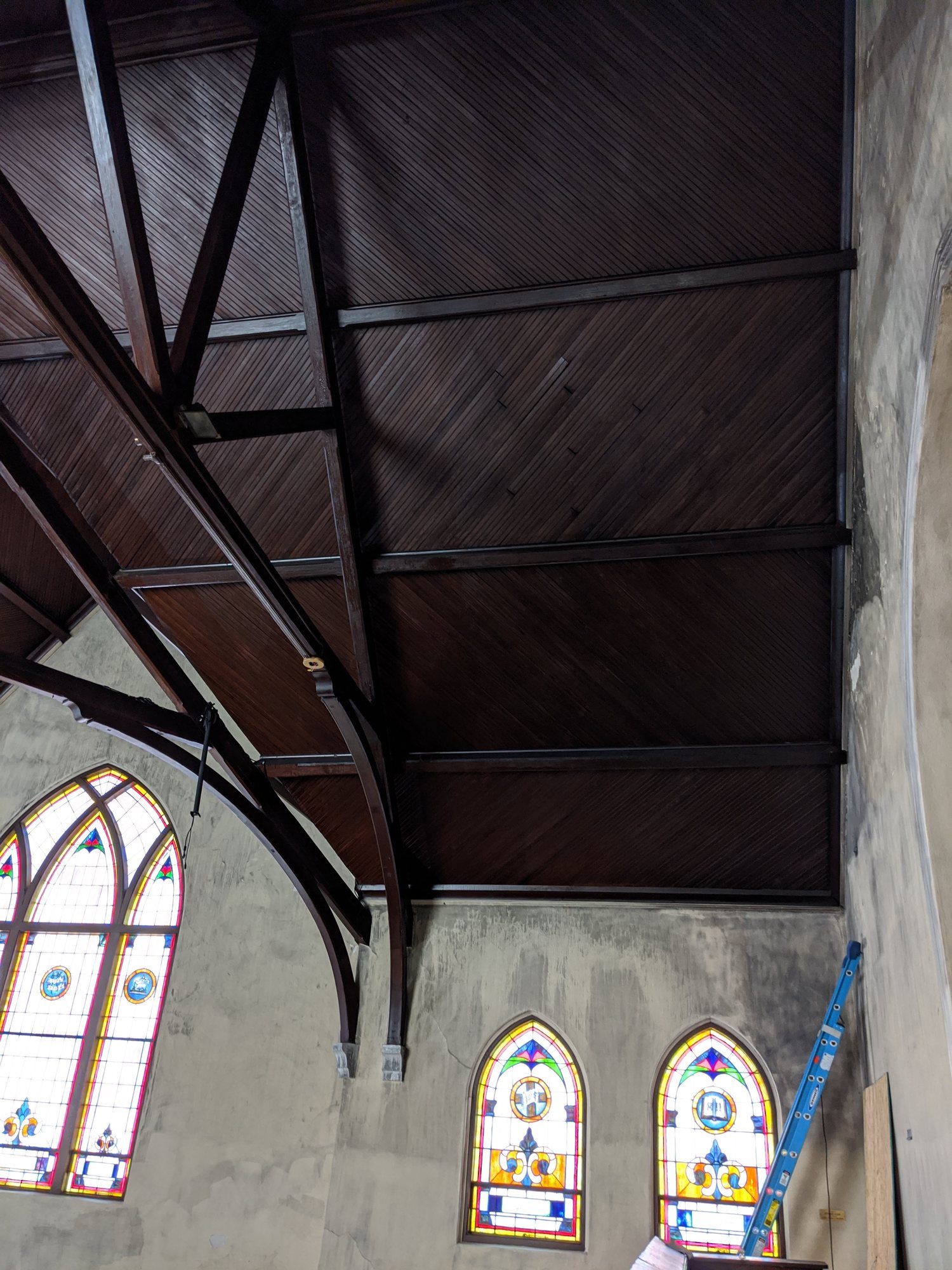 Cleaned wood ceiling and trusses above stained glass after soot removal.