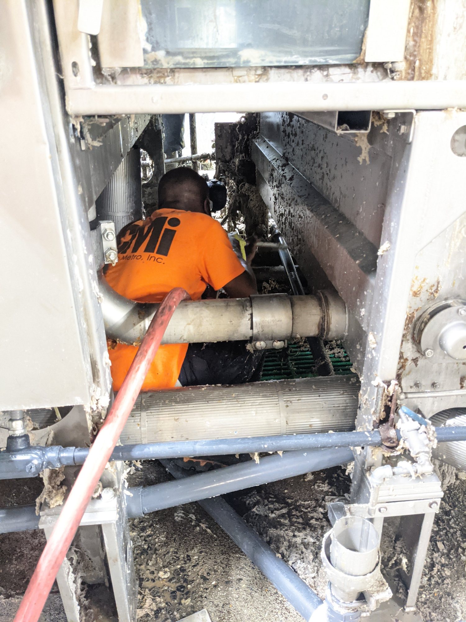 A CMI tech crawls inside a textile machine frame to vacuum out packed lint and fiber.