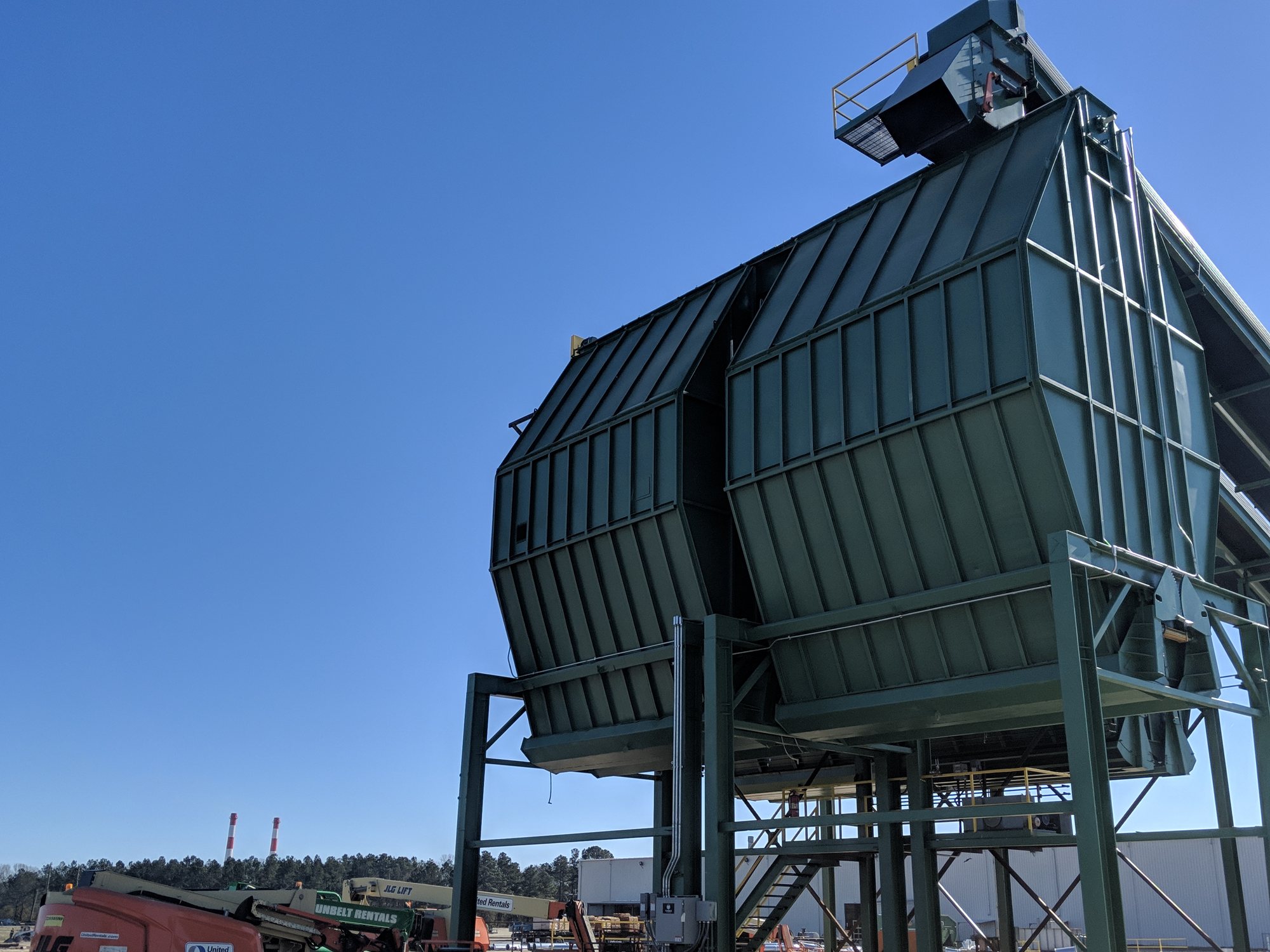 After: the dust collector finished in fresh green coating against a clear sky.