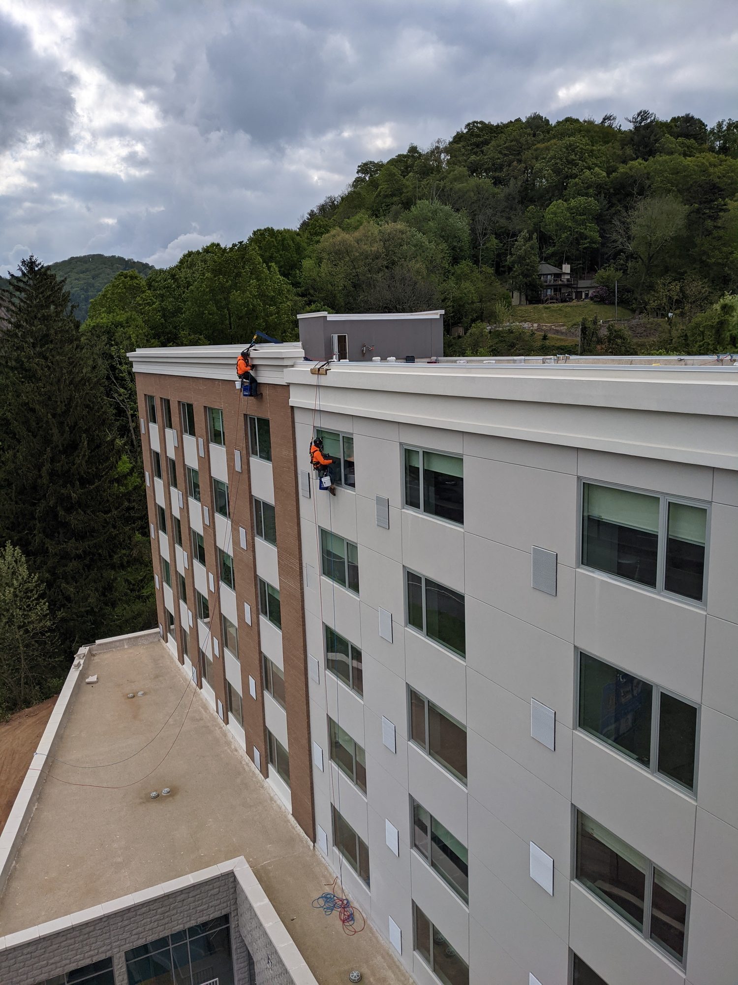 Two CMI rope access techs on separate drops down a six-story hotel facade in Asheville.
