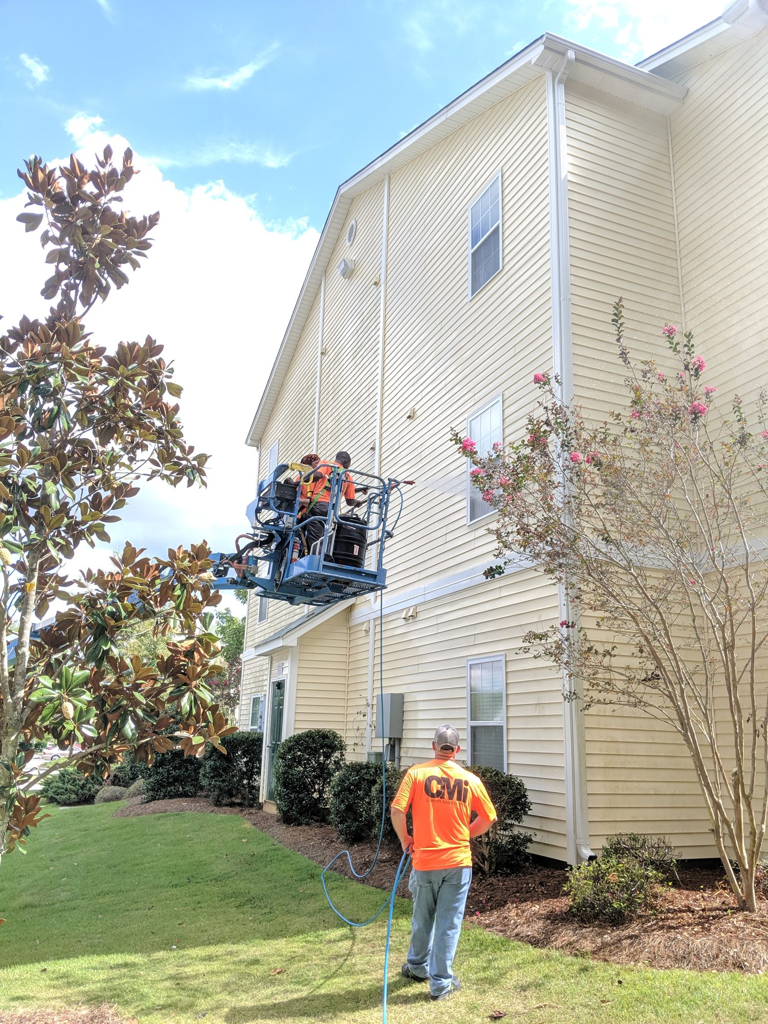 CMI crew washing an apartment building end wall from a boom lift.