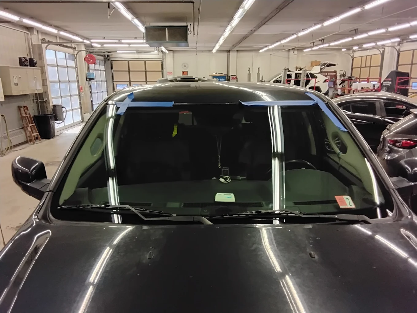 Site Auto Glass technician installing a new windshield on a sedan
