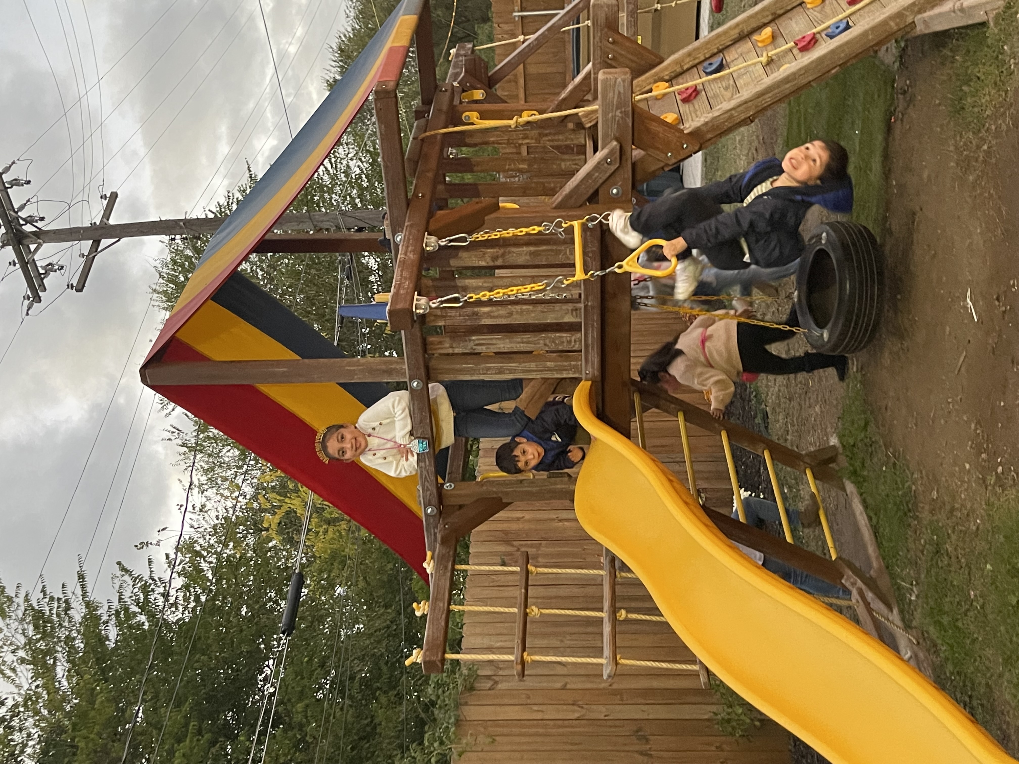 Children playing on the wooden slide and swing set in the outdoor park area