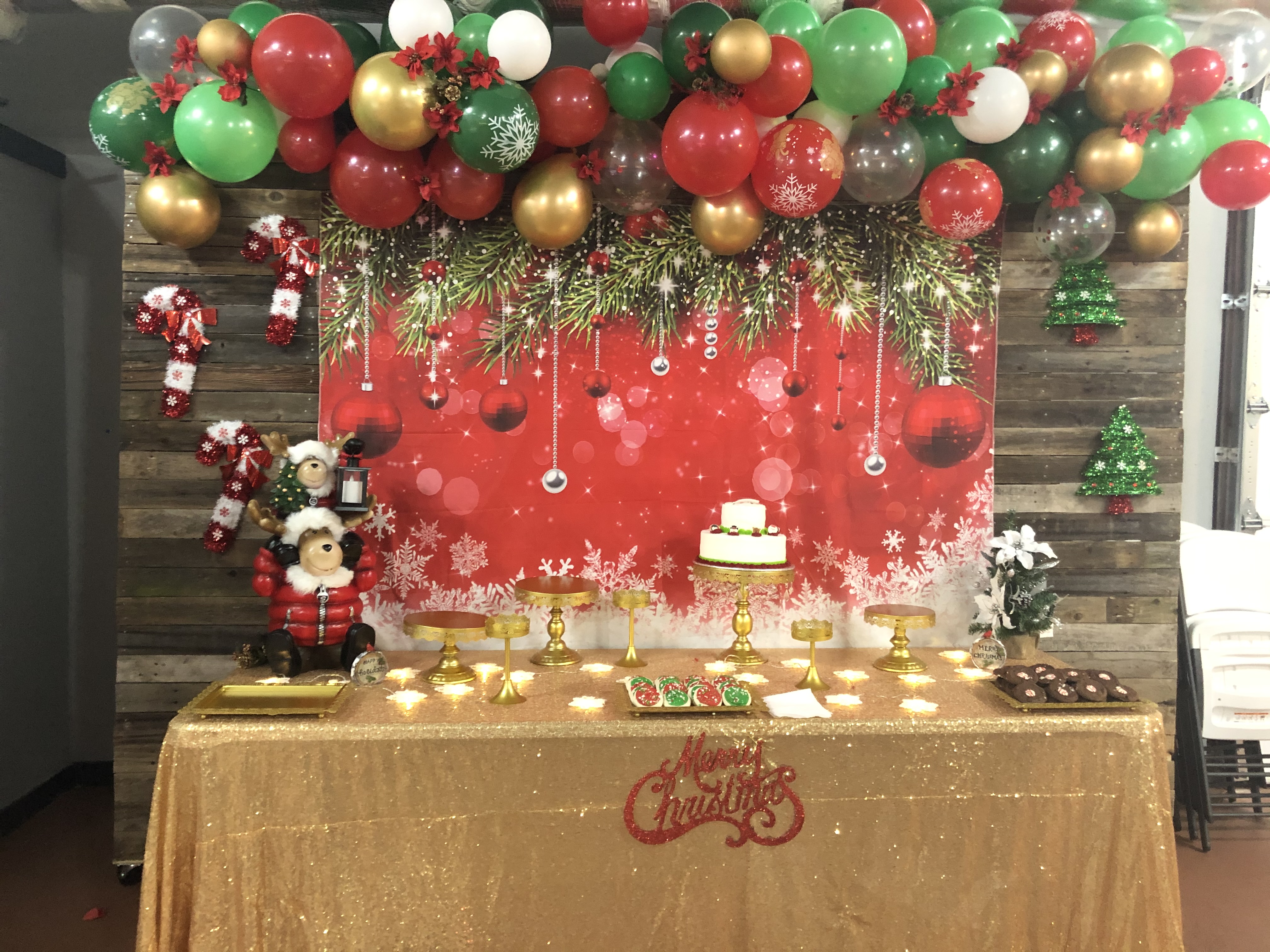 Dessert table with a balloon garland backdrop decorated for a holiday party
