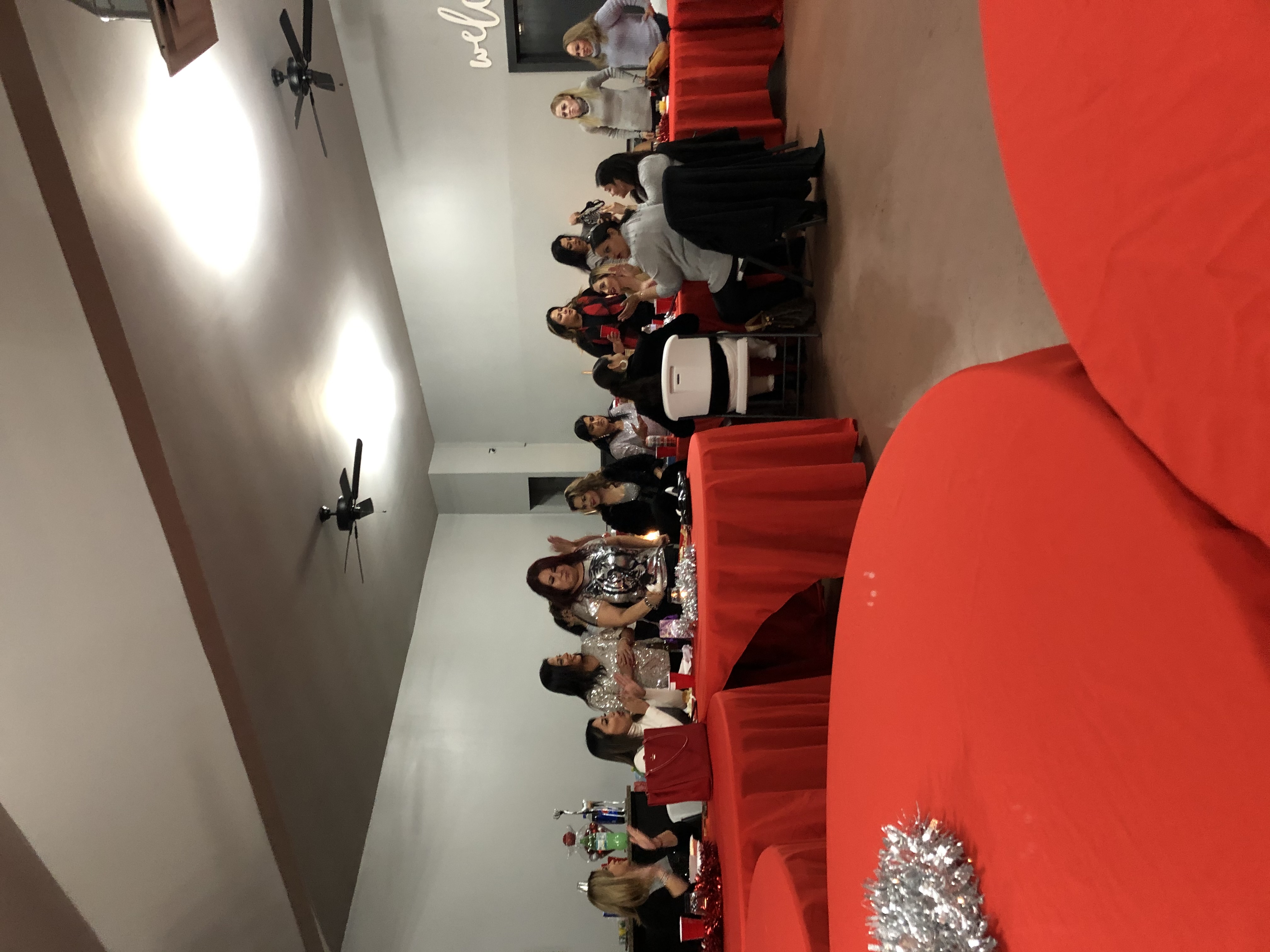 Guests seated at round tables with red linens during a party in the hall