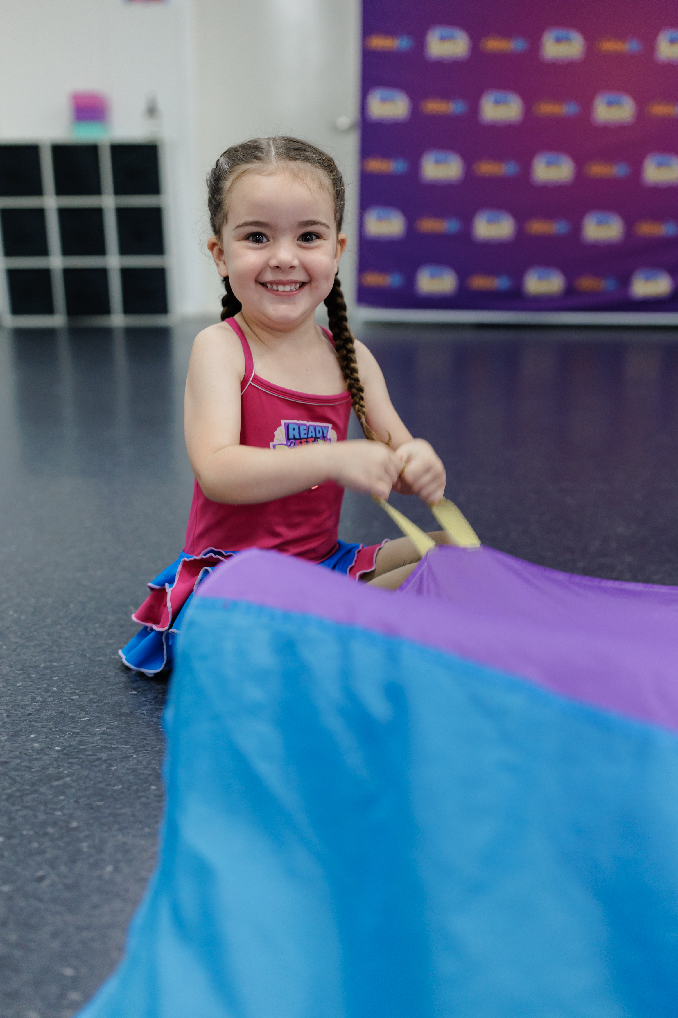 Pre-school student holding a parachute and smiling at KICO Dance Studios. This moment captures the fun and creativity of our pre-school dance classes, fostering confidence and joy in every child.