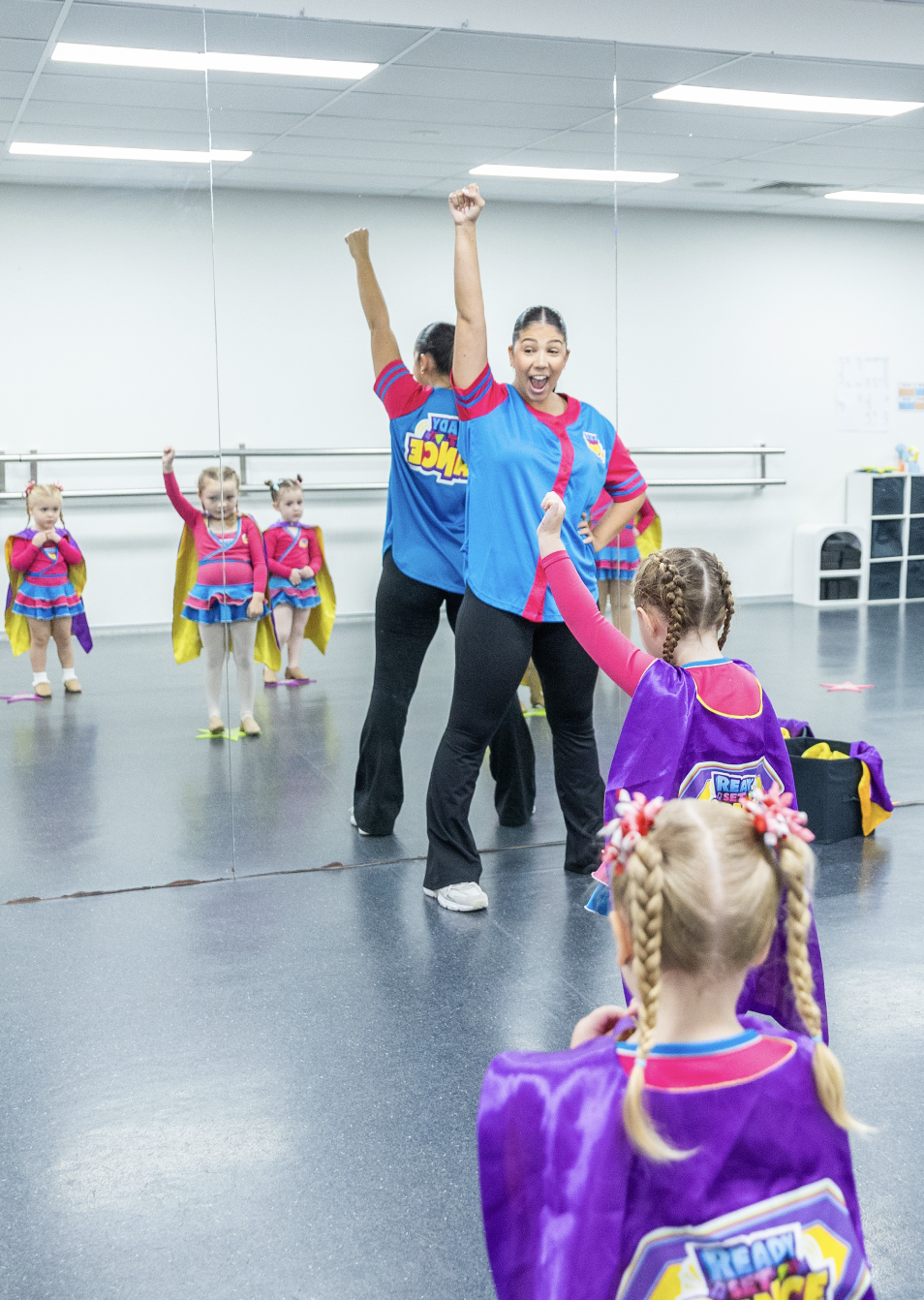 Smiling teacher leading a fun Ready Set Dance pre-school class at KICO Dance Studios. The children are imagining being superheroes, building confidence and creativity through dance in a supportive environment.