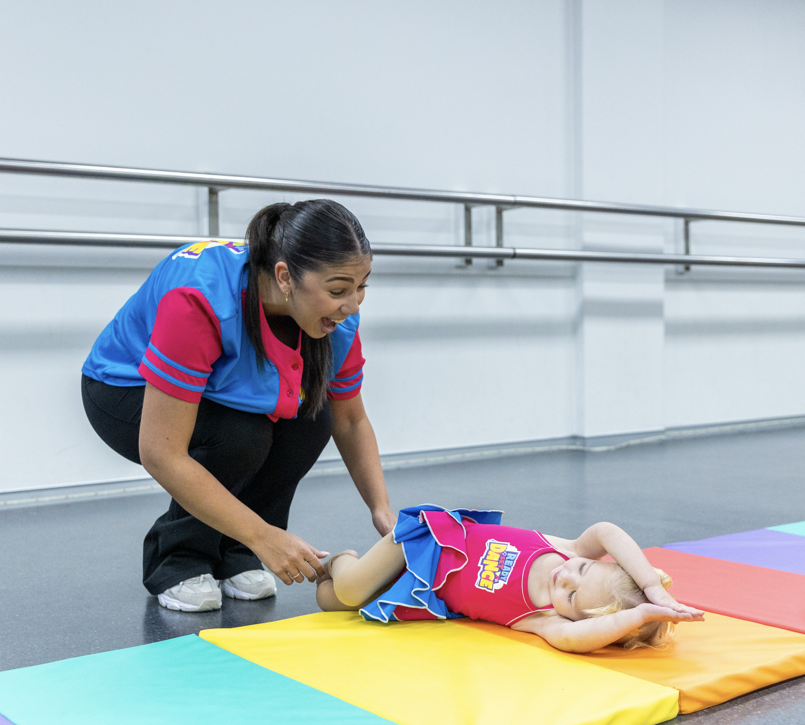 KICO Preschool dance teacher supporting a young student during a floor stretch, building flexibility, confidence, and foundational dance skills.