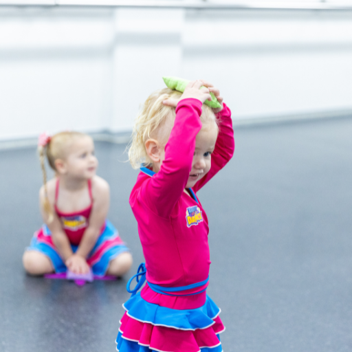 Toddler in a pink and blue Ready Set Dance uniform balancing a beanbag on her head during a preschool dance class at KICO Dance Studios in Bargo NSW.