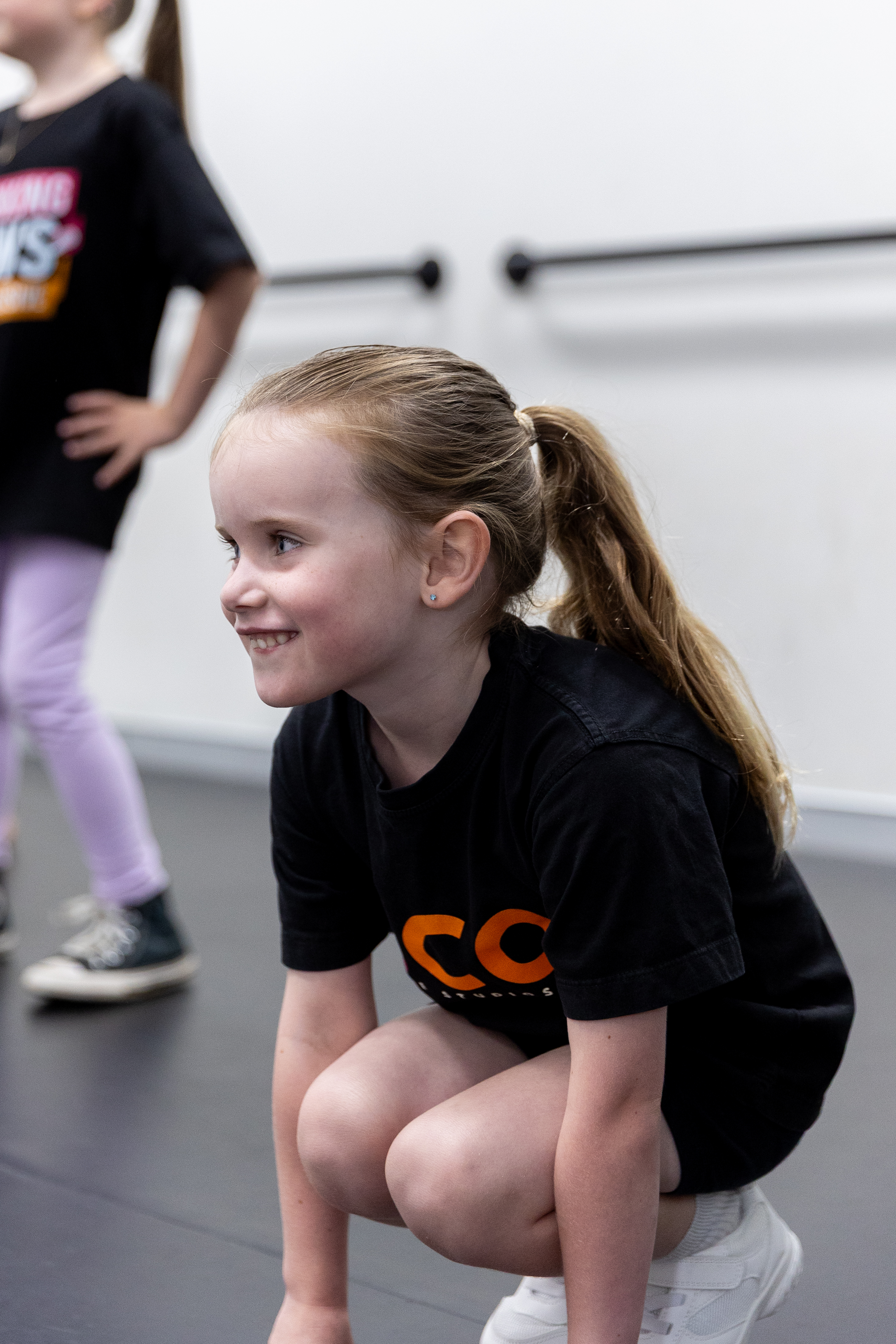 Kindergarten and Year 1 student smiling at their teacher during the roll-marking circle at KICO Dance Studios. Building confidence and connection through kids' dance classes in a supportive environment.