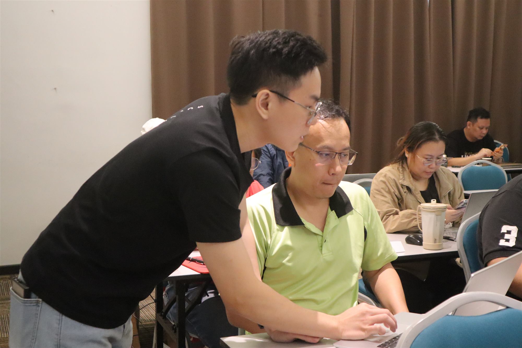 Ethan Foo helping a business owner set up his online sales system
