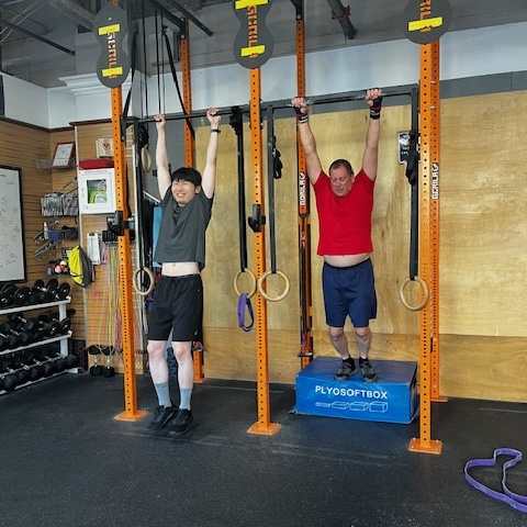 Two Empower athletes hanging from a bar