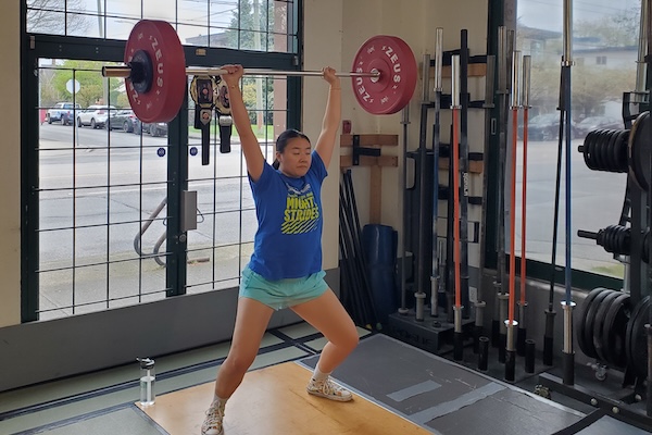 Empower member Tempo doing an overhead barbell lift