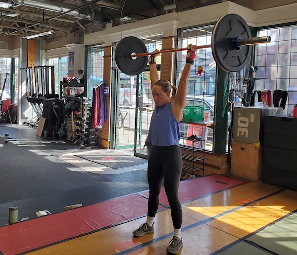 Empower member Pepper with an overhead barbell lift