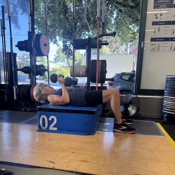 Empower member doing a floor press with dumbbells