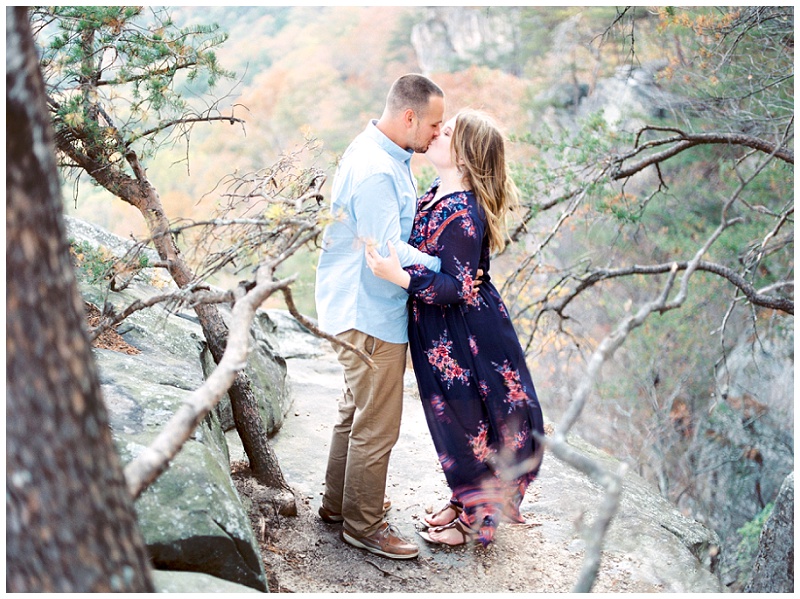 Engaged couple looking at each other with sunset rock in the distance, Chattanooga TN.