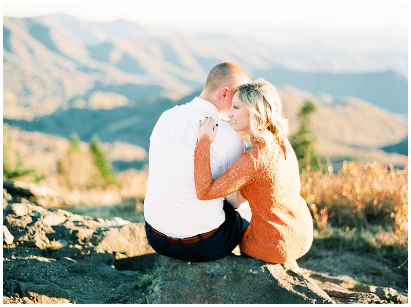 Couple on Roan Mountain sitting on a rock hugging each other.