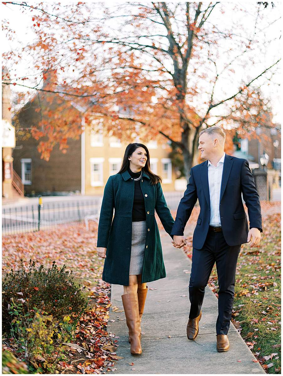 Couple walking through golden leaves during fall engagement session