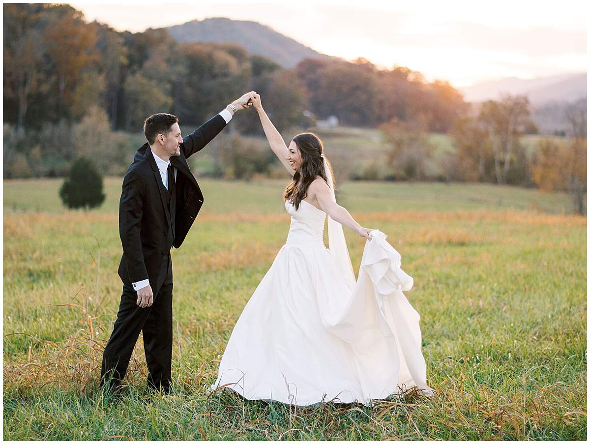 Bride and groom walking through field at sunset