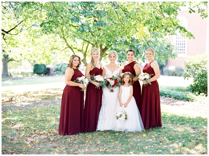 Bride posing with bridesmaids in burgundy dresses Bride posing with bridesmaids in burgundy dresses