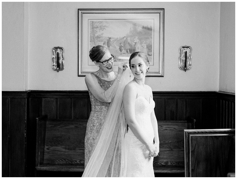 bride looking out window with mom before ceremony