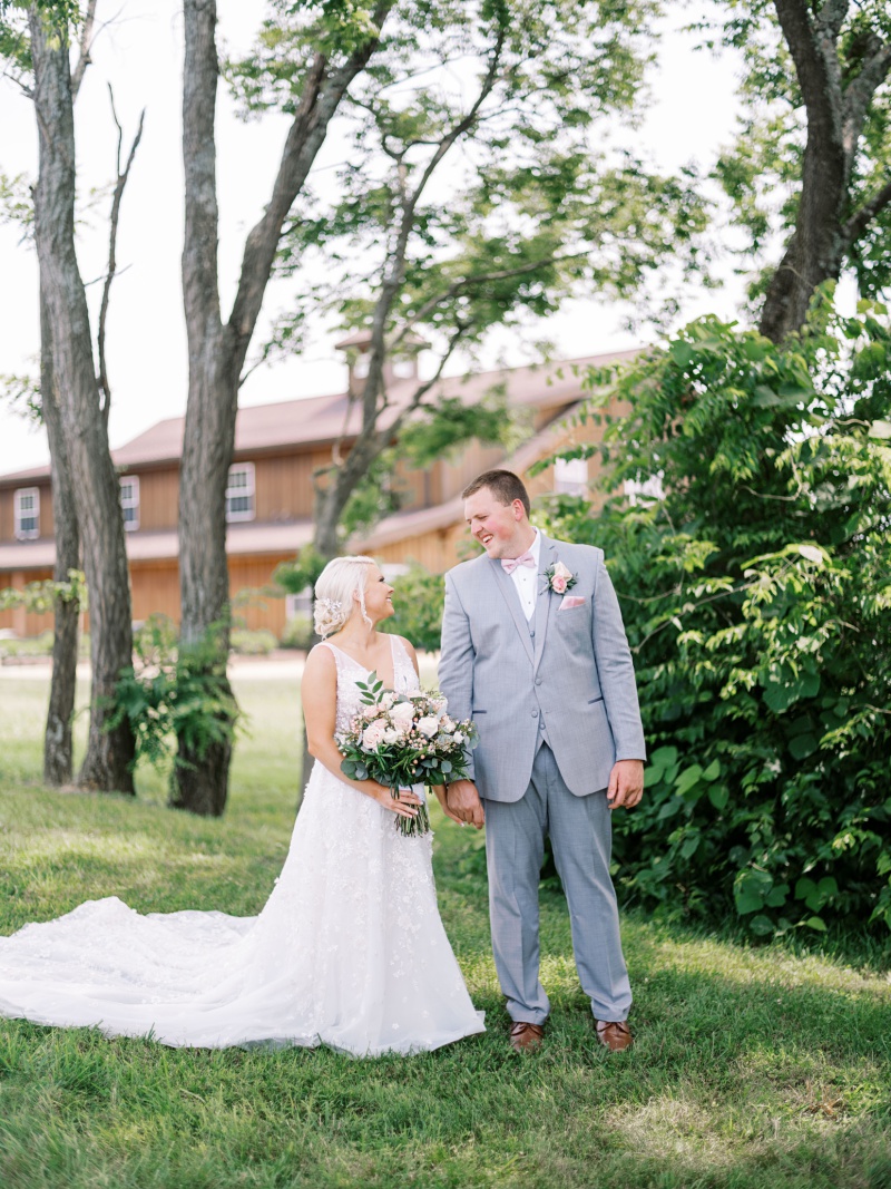 Bride and groom walking through farmland at barn venue