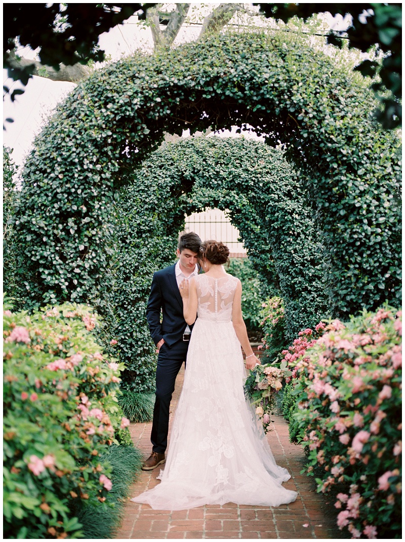 Bride standing with groom among roses at River Oaks Garden Club
