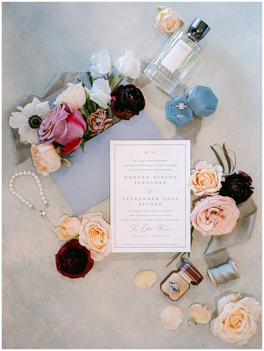The Olde Farm wedding flat lay featuring rings, florals, and stationery