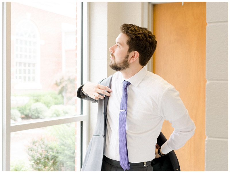 groom putting on jacket wedding morning