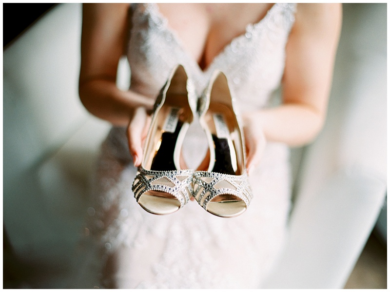bride holding wedding shoes morning of her wedding while getting ready