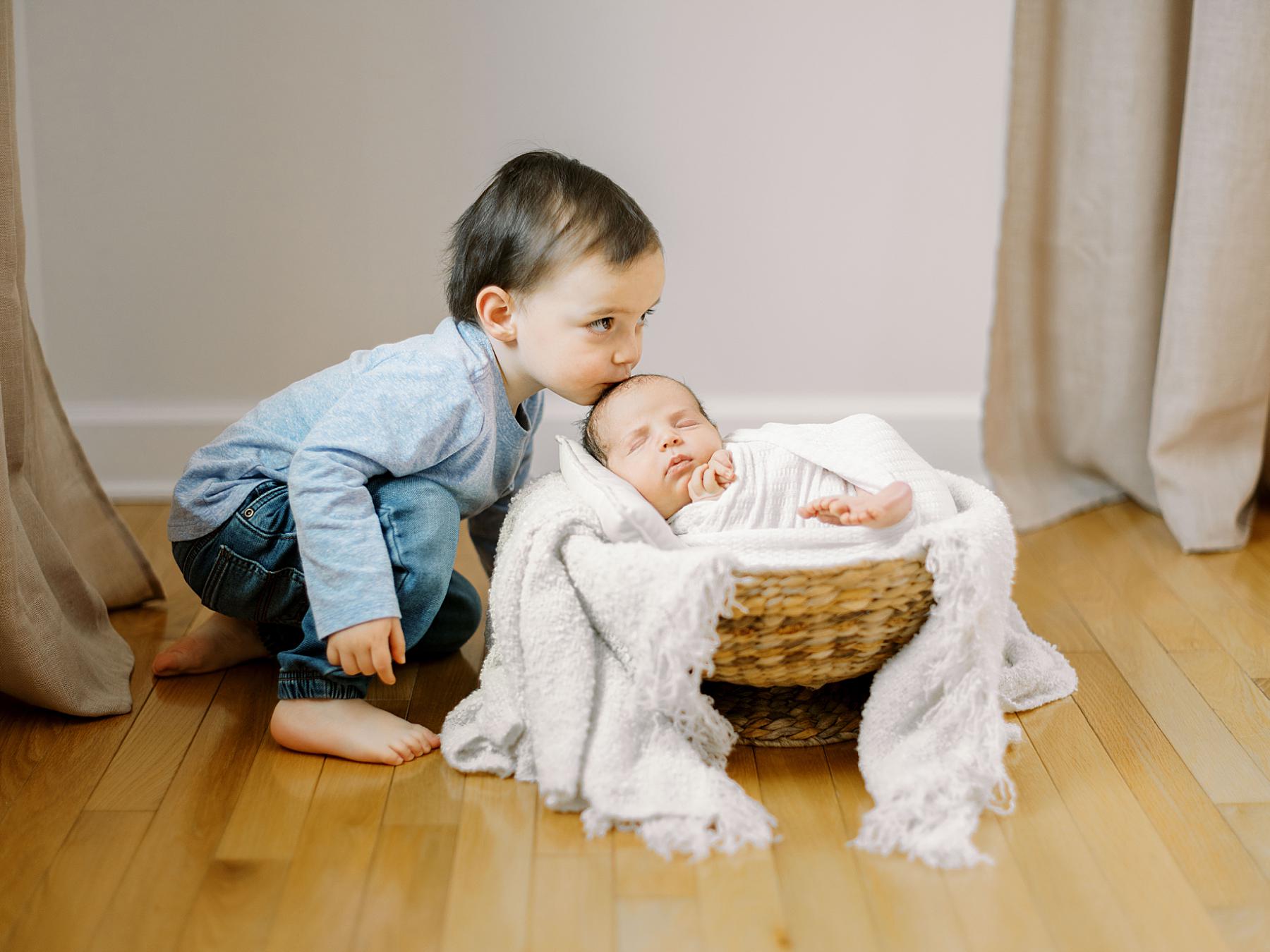 Three-year-old big brother gently looking at his newborn baby brother
