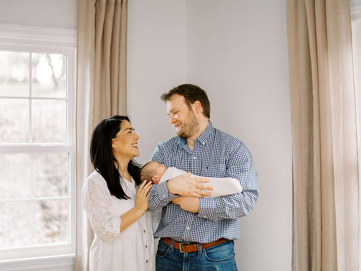 Parents embracing while holding their newborn baby boy during an at-home session