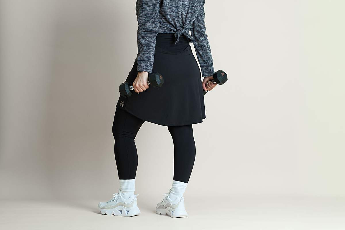 Girl holding weights while wearing a black skirted legging