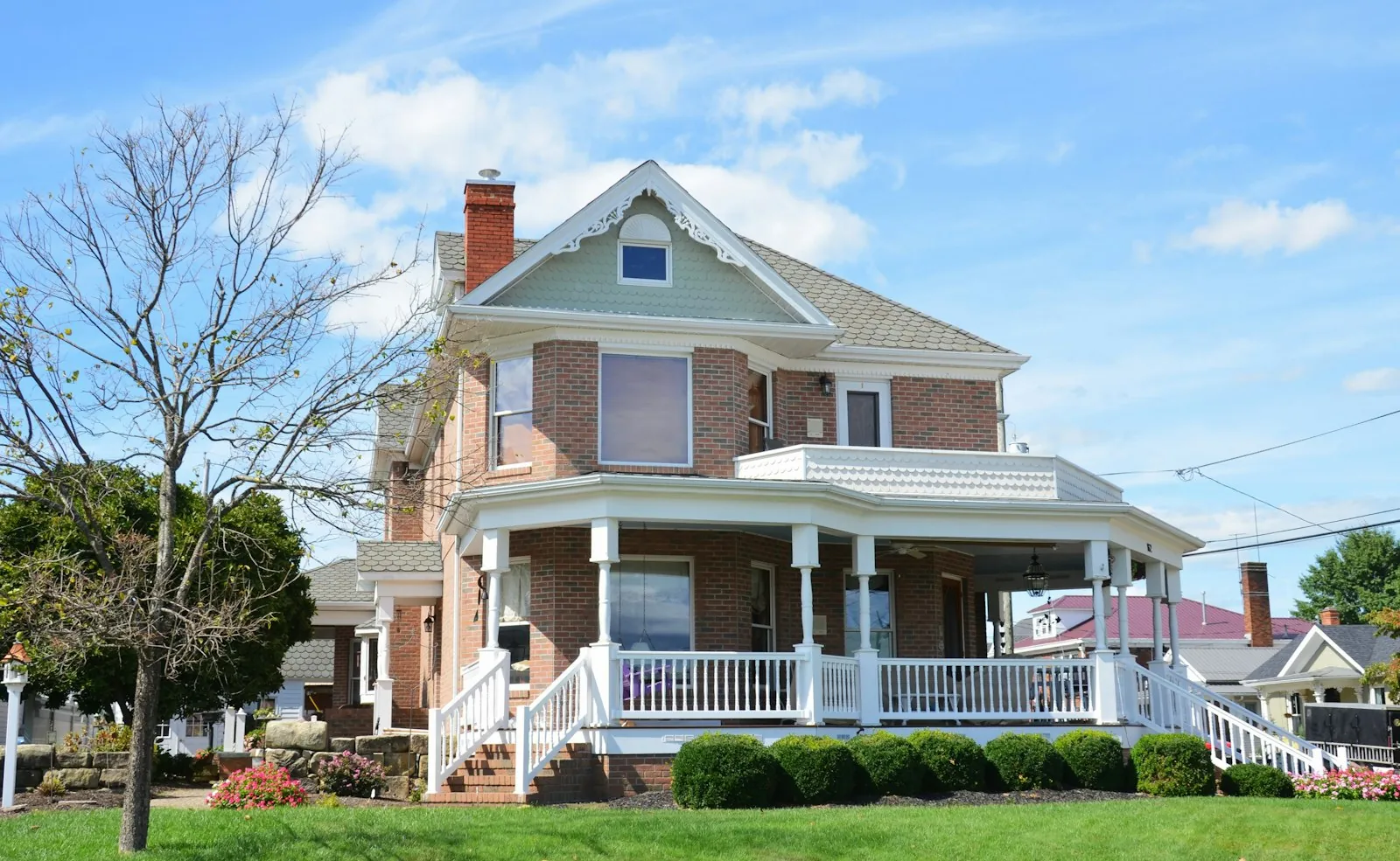 A brick house with a white wrap-around porch