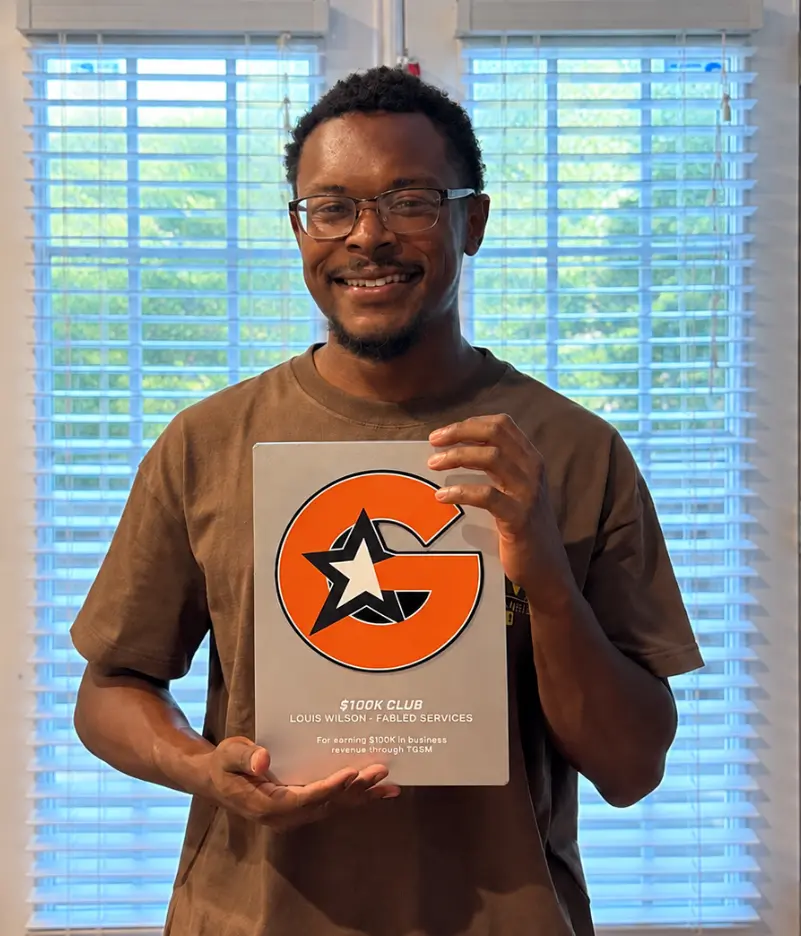 Louis Wilson of Fabled Services holding his official TGS Marketing $100K Club award plaque