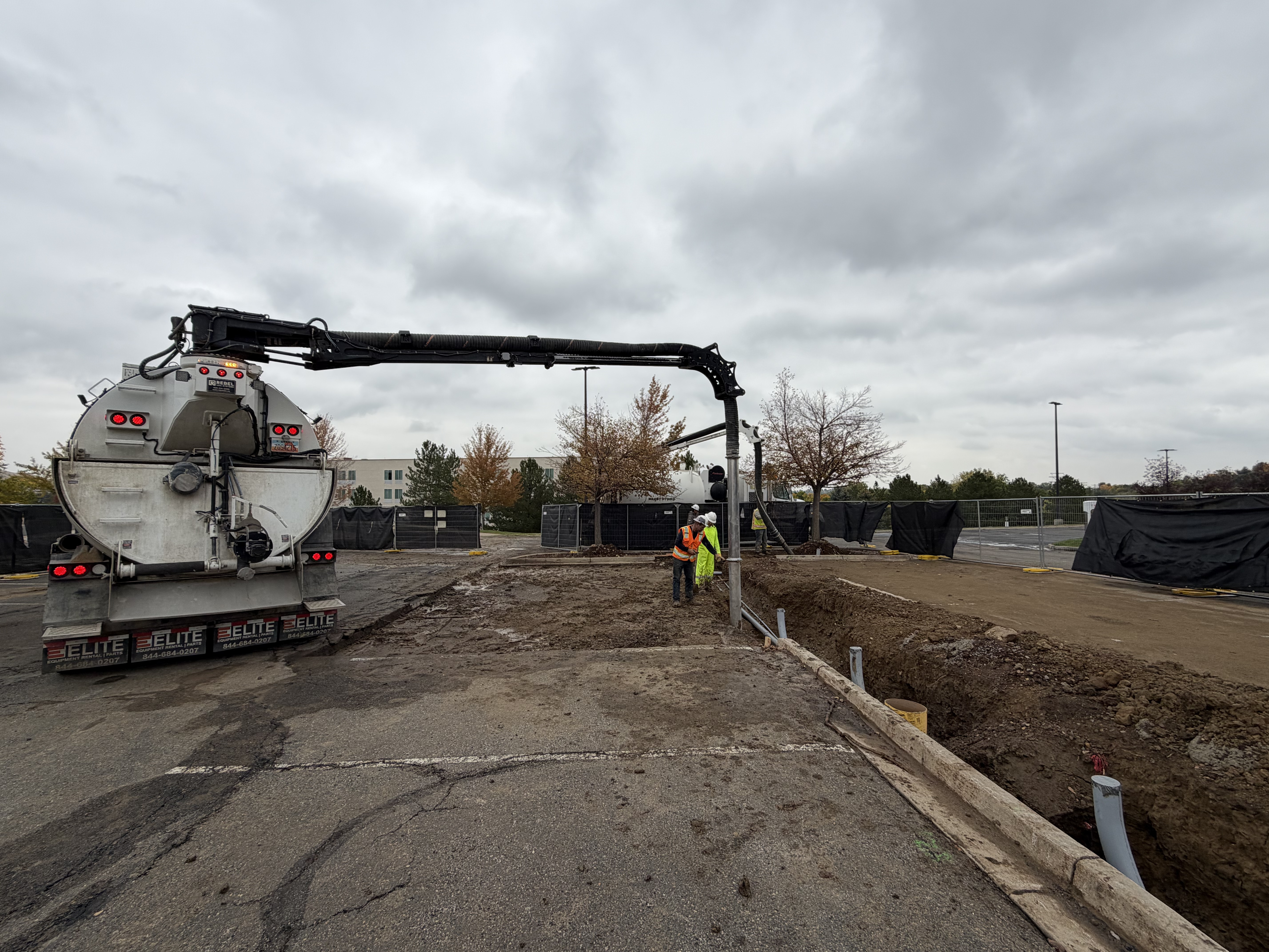 Vacuum truck performing hydrovac excavation trenching work at construction site