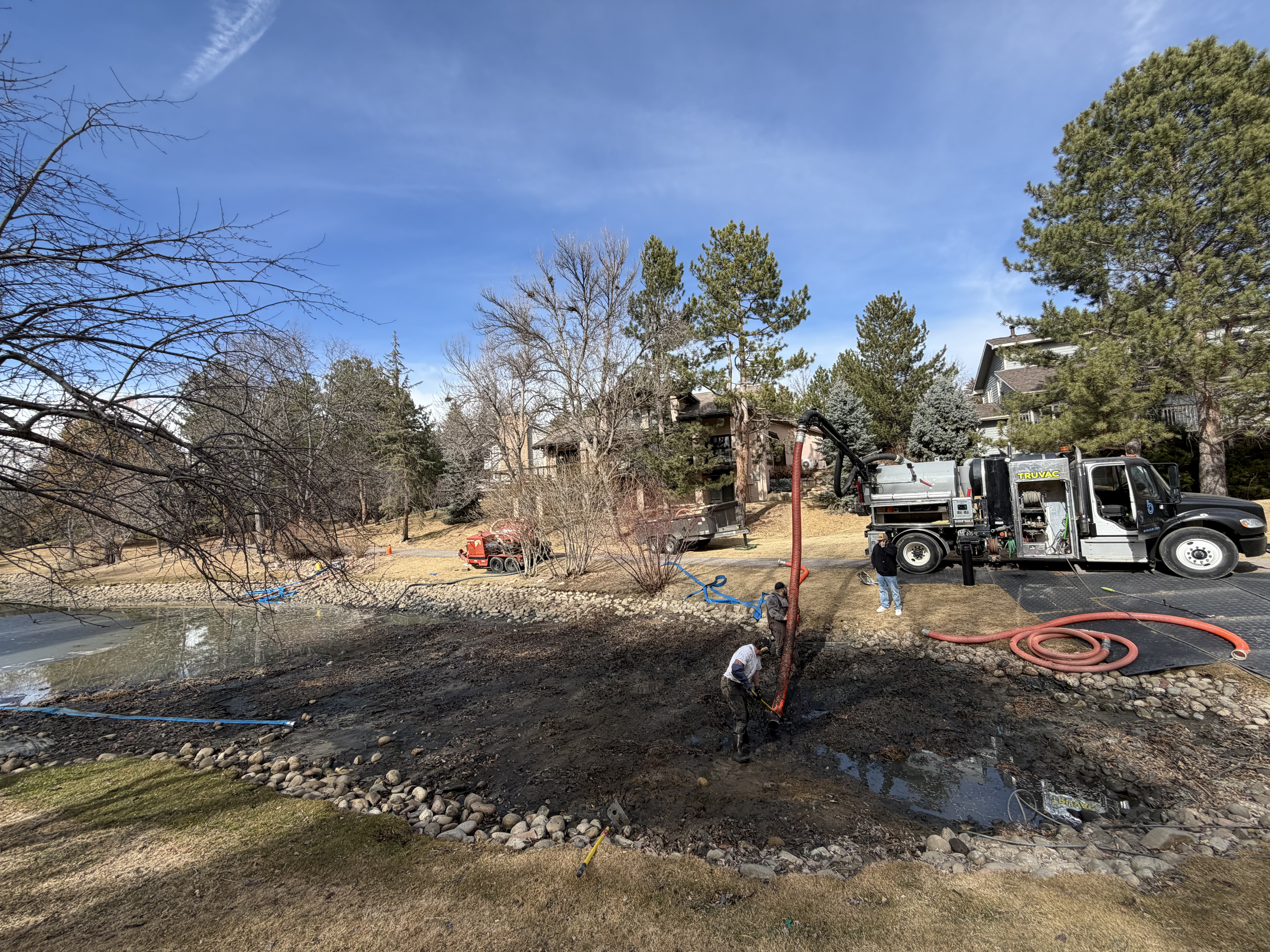 Vacuum truck removing sludge from pond during hydrovac excavation service