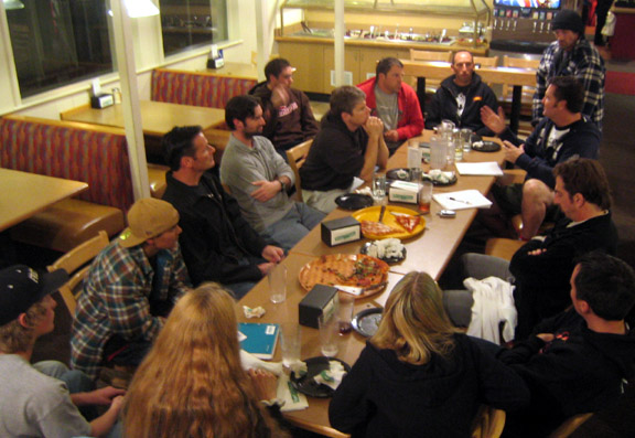 Skatepark advocates gathered around restaurant tables with notebooks and pizza