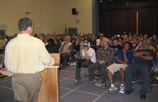 Public skatepark meeting with a speaker addressing a large seated audience