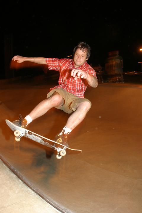 Skateboarder performing a frontside ollie in the North Little Rock skatepark bowl