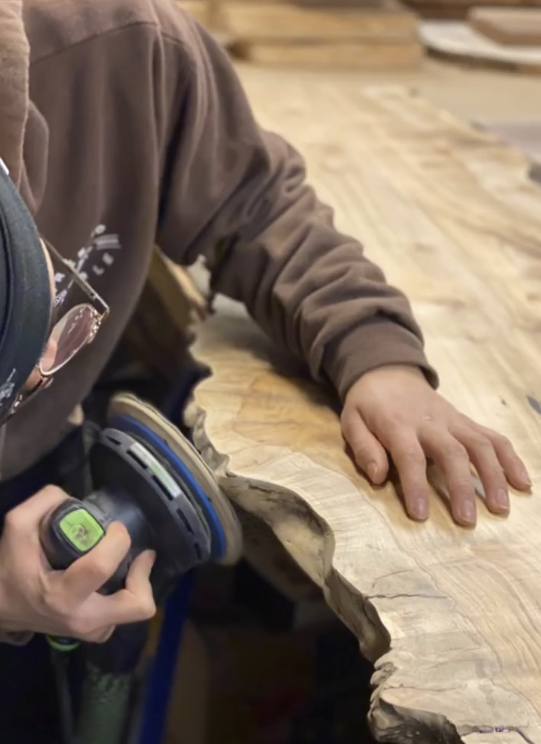Hands shaping a wooden table
