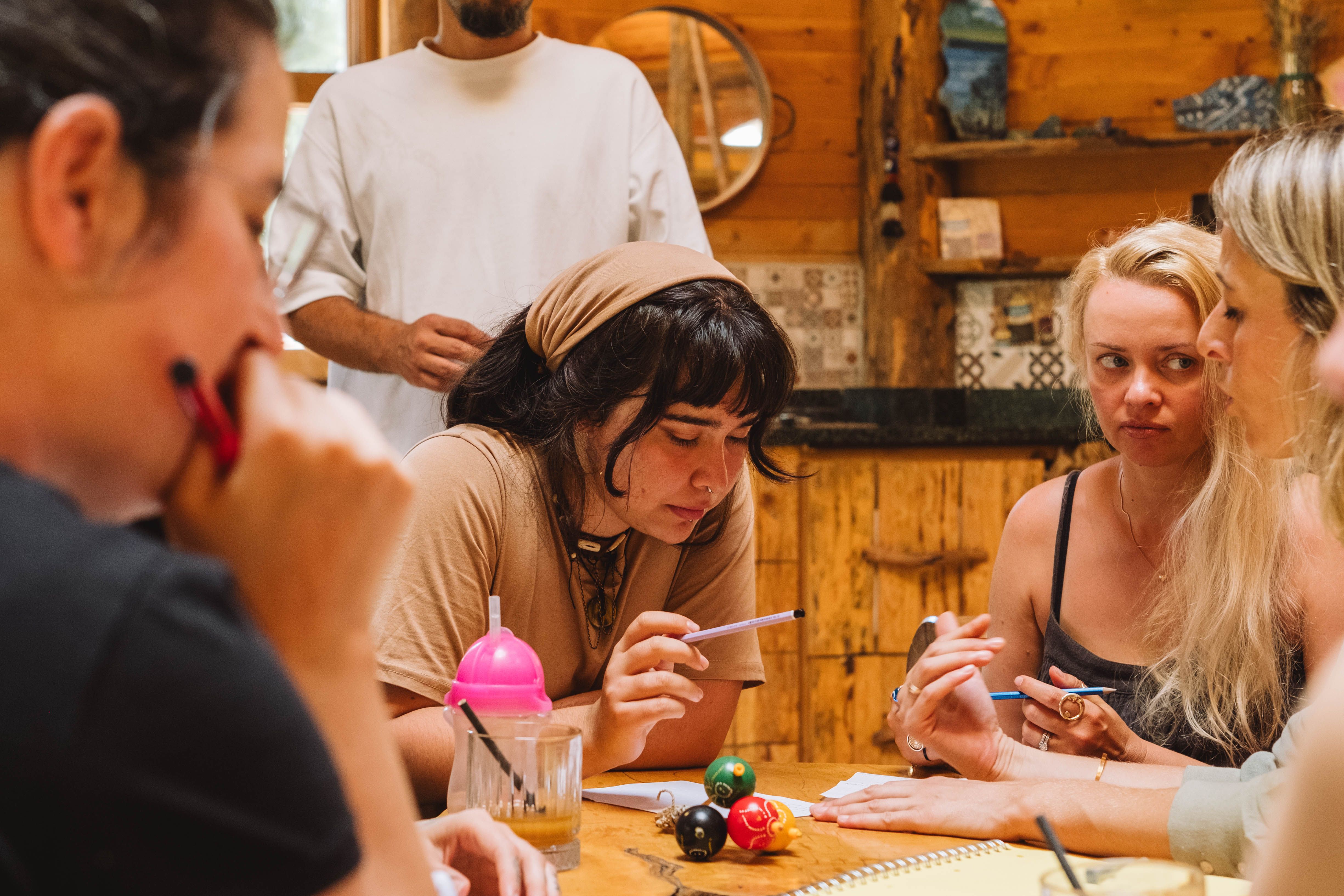 People gathered around a wooden table talking and writing