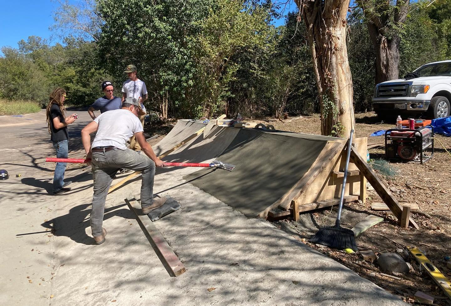 A crew shaping and finishing a small concrete skate transition in Austin