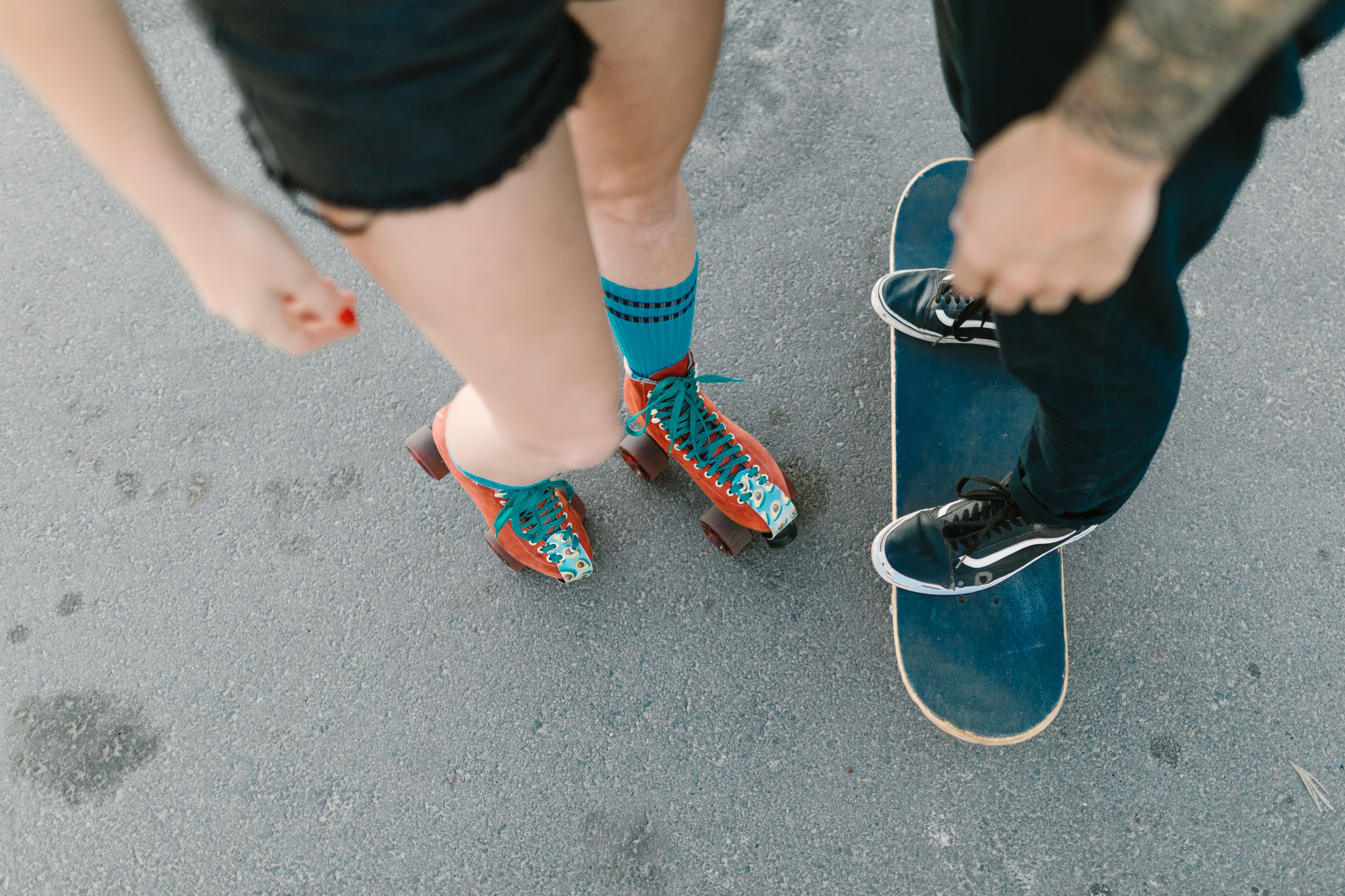 A skateboarder and roller skater standing together on pavement